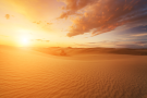 Sunrise over the desert with clouds along the horizon.